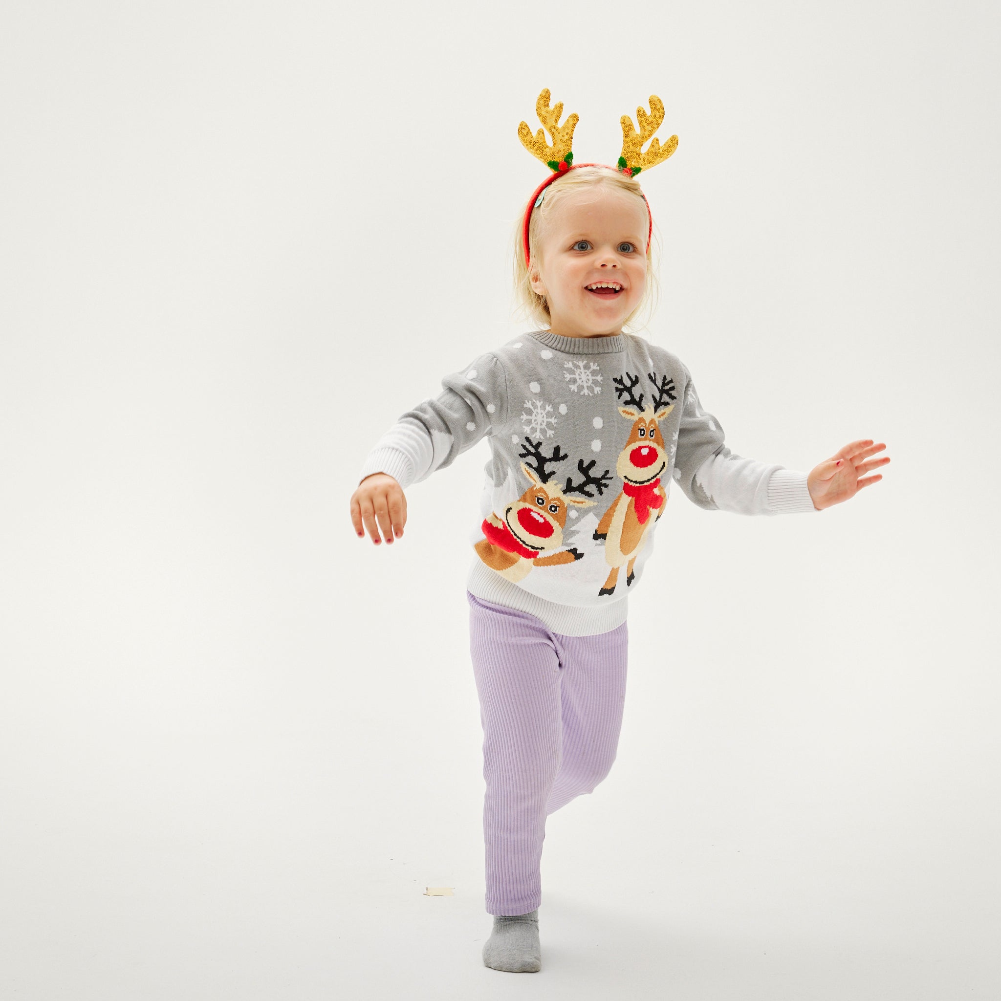Kinder Weihnachtspullover mit Rentiermotiv, grauer Pullover kombiniert mit lilafarbenen Hose, weihnachtspyjama geeignet.